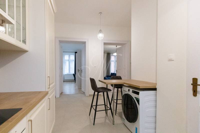 Chodba v 3-pokojovém bytě s pračkou, židlemi a kuchyňskou linkou.