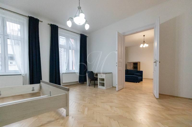 Interiér 3-pokojového bytu s podlahou s dřevěným dekorem, nábytkem a lustrem.