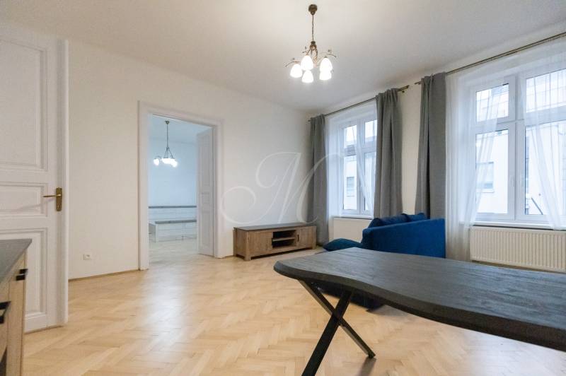 Obývací pokoj v 3-pokojovém bytě s podlahou s dřevěným dekorem a modrou sedačkou.