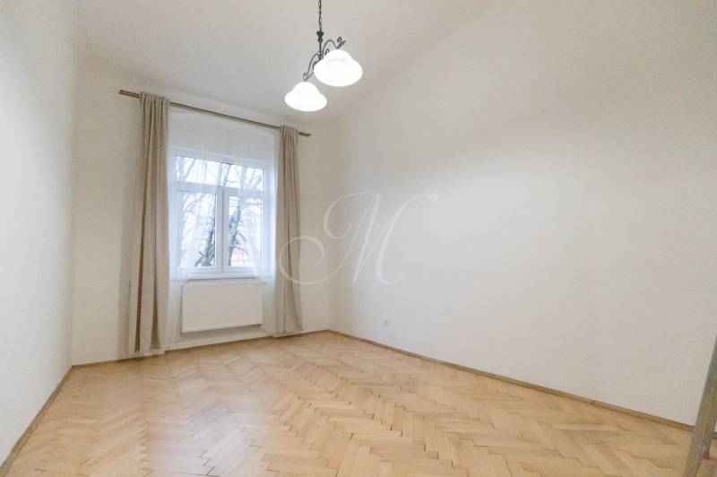 Pokoj v 3-pokojovém bytě s podlahou s dřevěným dekorem a velkým oknem.