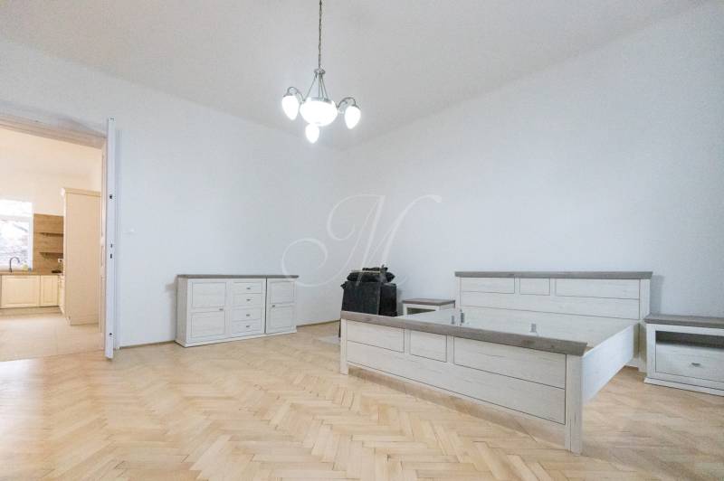 Ložnice s postelí, nábytkem a podlahou s dřevěným dekorem ve 3-pokojovém bytě.