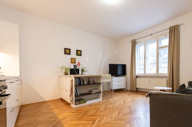 Obývací pokoj v 2pokojovém bytě se světlým nábytkem a podlahou s dřevěným dekorem.