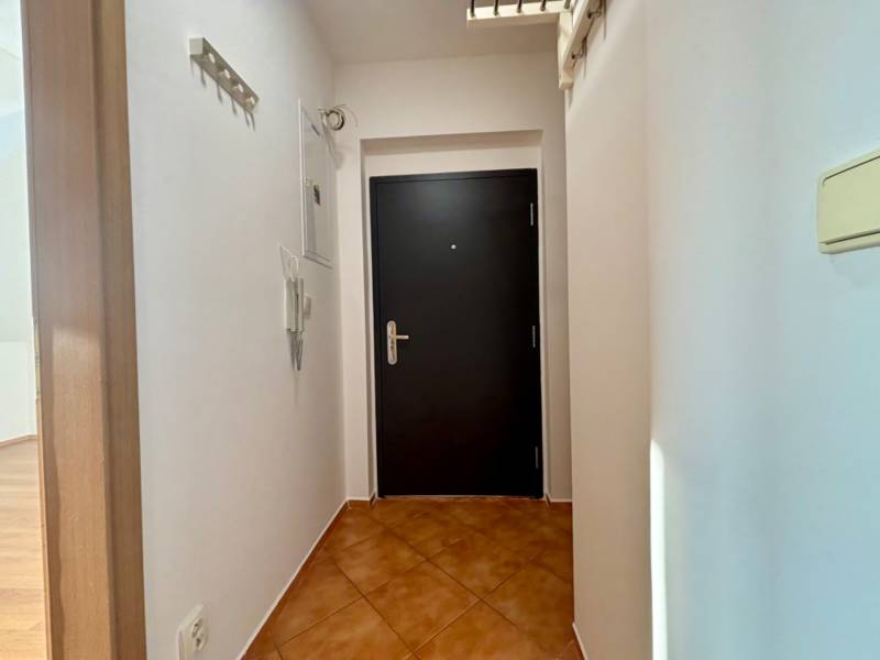 Vstupní chodba s tmavými dveřmi v 2pokojovém bytě, bílé stěny a dlažba.