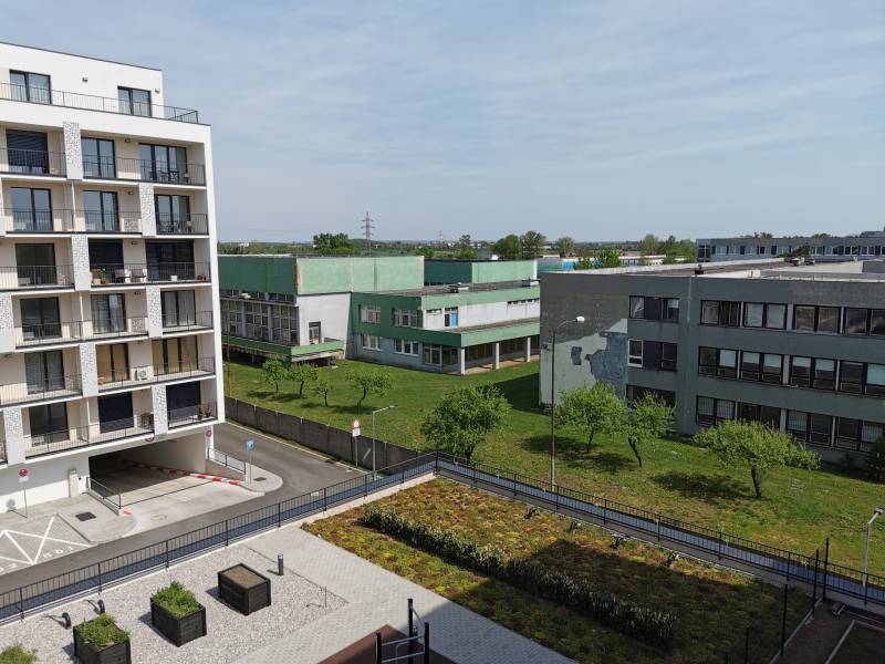 Pohled na obytné budovy a zeleň na Eduarda Wenzla v Bratislavě-Rači, garáže vpravo.