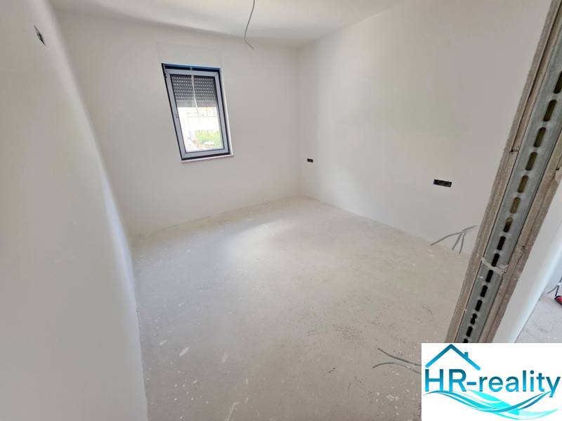 Světlý pokoj s bílými stěnami a oknem značky HR-reality v Rekreačním apartmánu.