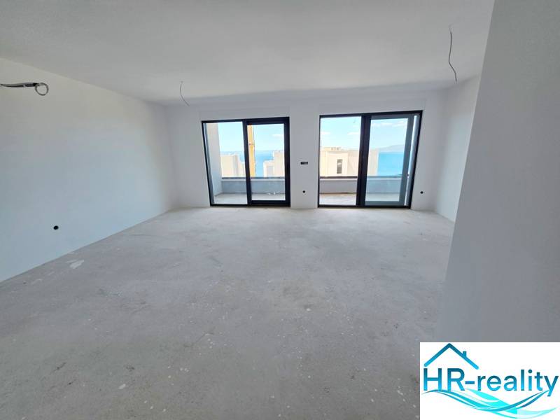 Interiér rekreačního apartmánu s výhledem přes velká okna na moře.