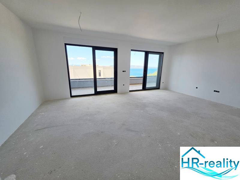 Světlá místnost v rekreačním apartmánu s velkými okny s výhledem na moře.