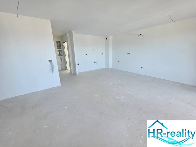 Rekreační apartmán s čistými bílými stěnami a prostornou podlahou s dřevěným dekorem.