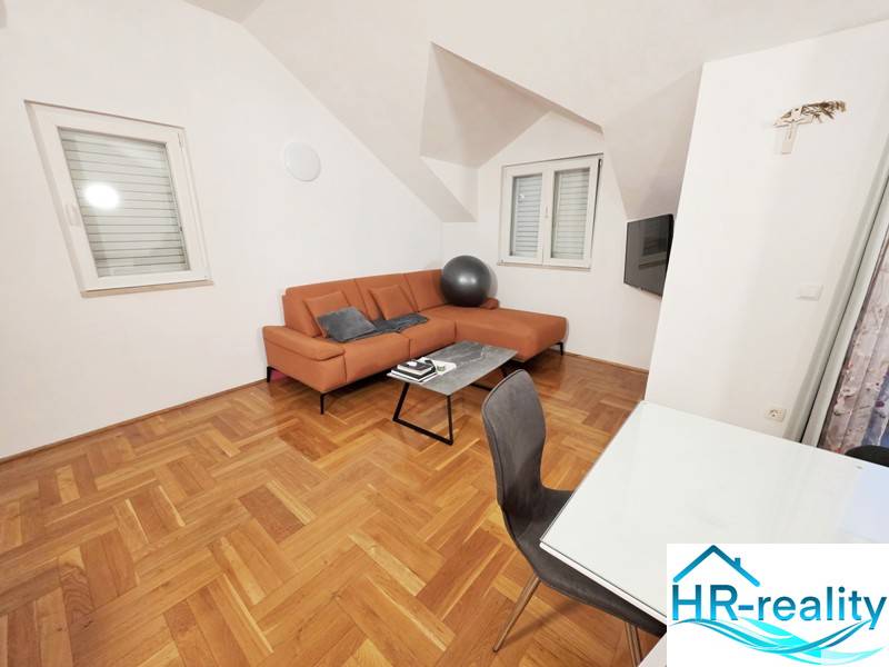 Rekreační apartmán s oranžovou sedačkou a podlahou s dřevěným dekorem.