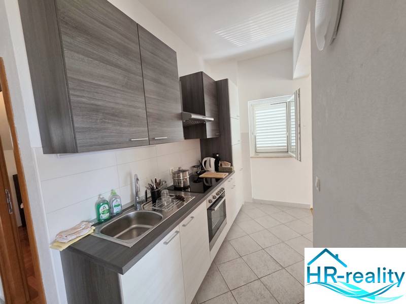 Kuchyně rekreačního apartmánu s moderním vybavením a oknem, které osvětluje prostor.