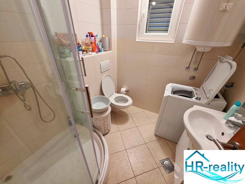 Koupelna v rekreačním apartmánu s toaletou, sprchovým koutem a pračkou.