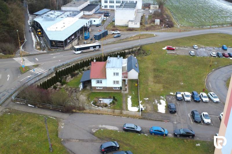 Rodinný dům na ulici SNP v Považské Bystrici, obklopený auty a zelení.