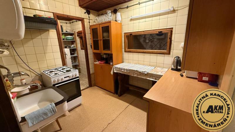 Kuchyně v chatě s plynovým sporákem, dřevěným dekorem a kuchyňskou linkou.