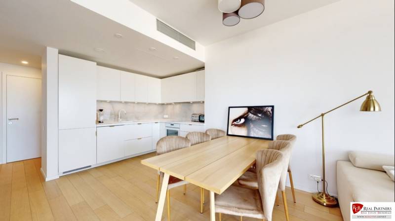 Kuchyně v 3-pokojovém bytě s podlahou s dřevěným dekorem, jídelním stolem a lampou.