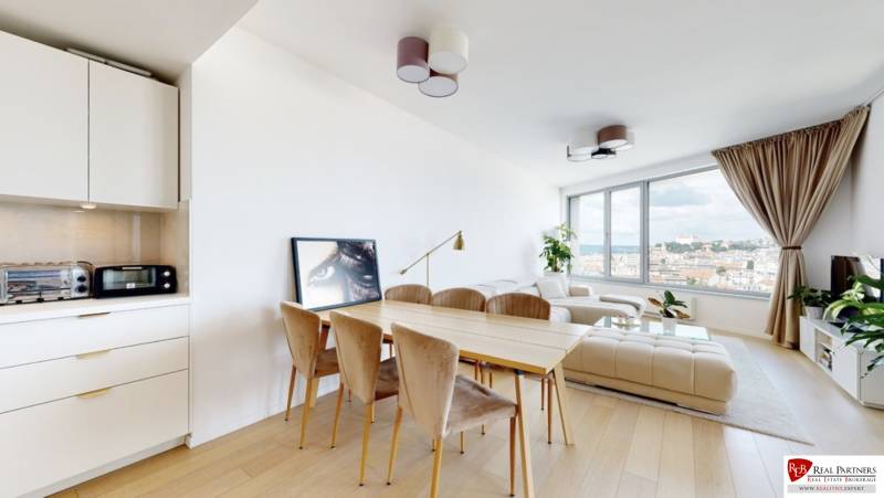 Světlý obývací pokoj s jídelním stolem, bílou sedačkou a výhledem, 3pokojový byt.