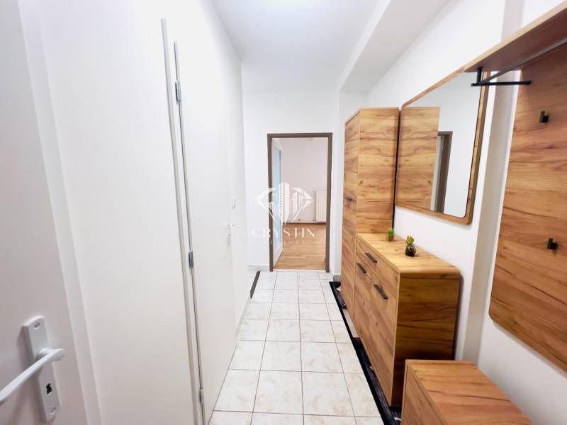 Chodba v 2-pokojovém bytě s dlažbou a dřevěným dekorem nábytku.