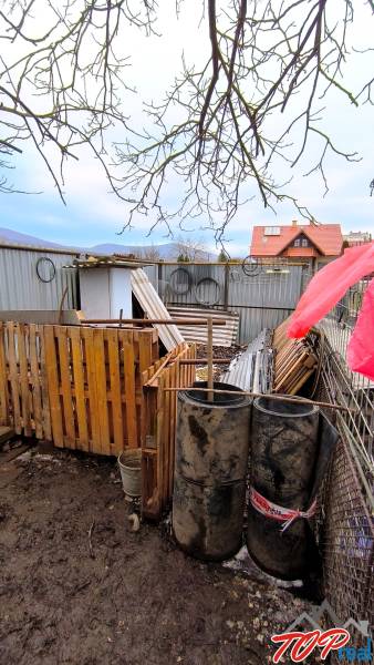 Pozemky - bydlení na Mierové ulici v Krásnohorskom Podhradí s materiály a sudy.