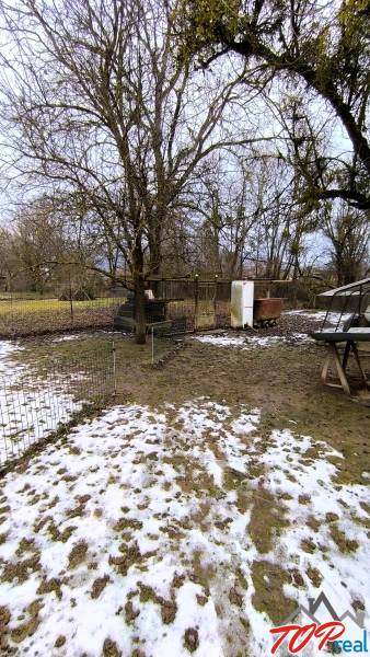 Pozemek na Mírové ulici v Krásnohorské Podhradí s trávou a sněhem, vhodný k bydlení.