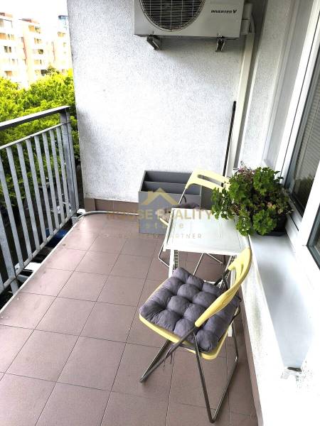 Balkon 2pokojového bytu s posezením a zelení, ideální pro relaxaci.