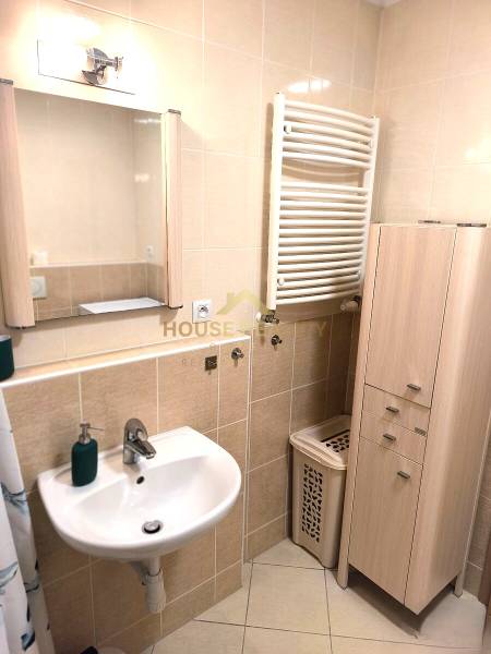 Koupelna s umyvadlem, zrcadlem a skříní v 2pokojovém bytě.