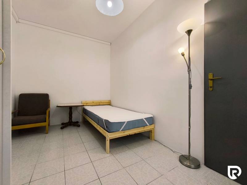 Jednolůžkový pokoj s křeslem a stojací lampou v rodinném domě.