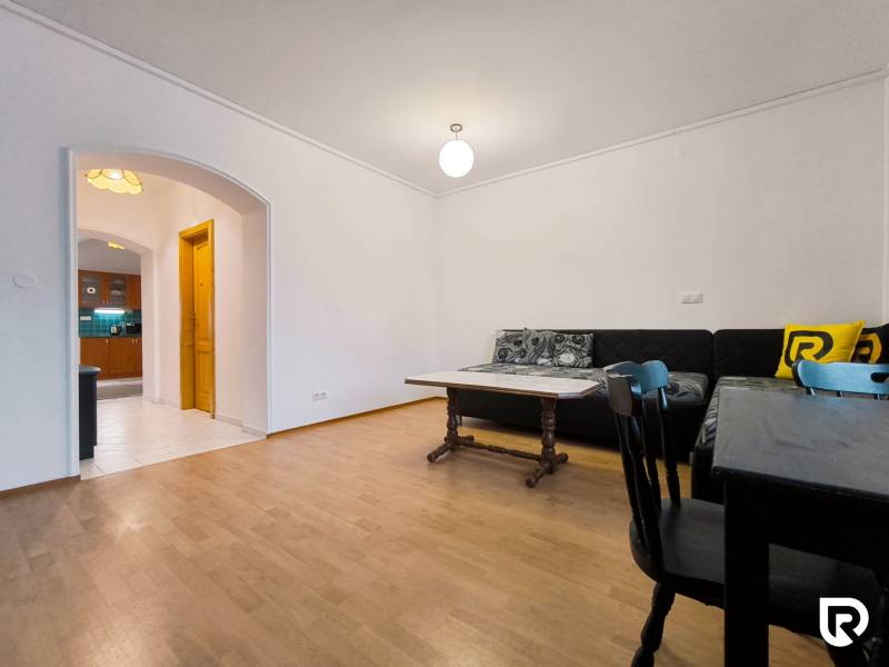 Obývací pokoj v rodinném domě s podlahou s dřevěným dekorem, sedačkou a jídelním stolem.