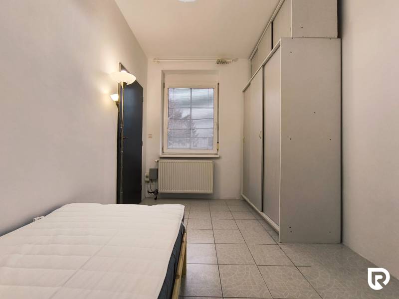 Ložnice v rodinném domě s postelí, vestavěnou skříní a dlažbou.