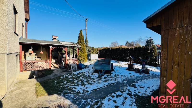 Zahrada rodinného domu ve Velkých Bielicích, Partizánske s přístřeškem a zasněženým trávníkem.