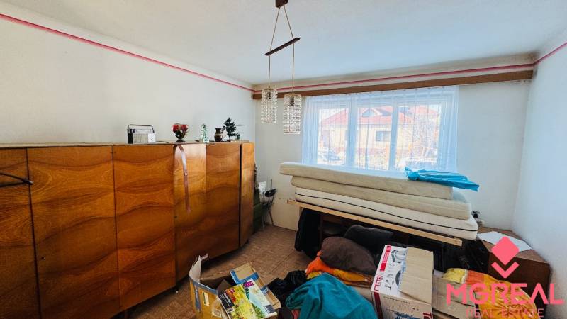 Pokoj v rodinném domě s dřevěným nábytkem, lustr a okno s výhledem.