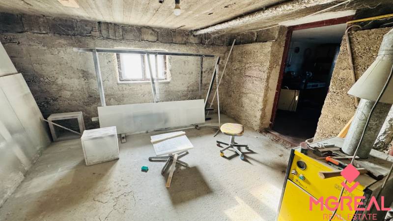 Suterénní prostor v rodinném domě s jednoduchým nábytkem a oknem.