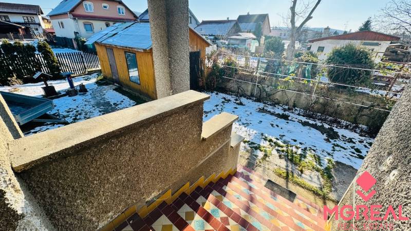 Zahrada rodinného domu ve Velkých Bielicích v Partizánském, s přístřeškem a sněhovou pokrývkou.