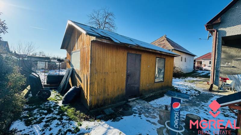 Za domem v Partizánskem, Velkých Bielicích, stojí dřevěná chatka na zasněženém dvoře.