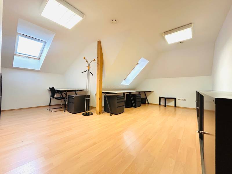 Kanceláře s podlahou s dřevěným dekorem, stoly, židlemi a střešními okny.