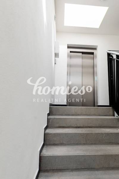 Schodiště k výtahu v budově s 3pokojovým bytem, světlý prostor.