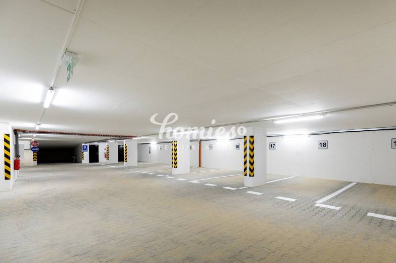 Podzemní parkoviště s jasným osvětlením a vyhrazenými parkovacími místy.