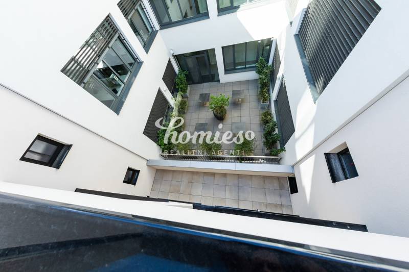 Vnitřní dvůr bytového komplexu v Nitře s terasovou dlažbou a zelení.