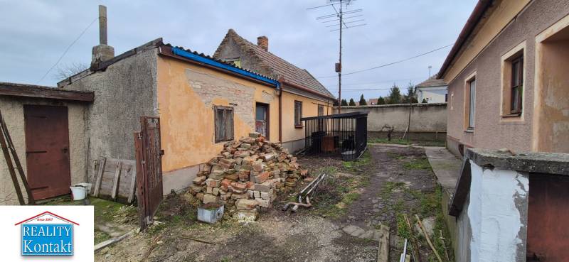 Rodinný dům ve Dvorech nad Žitavou s hromadou cihel a starou fasádou.