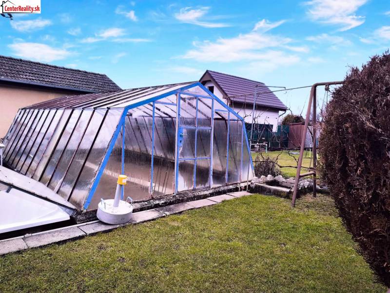 Zahrada v Partizánském s nadzemním bazénem zakrytým konstrukcí, houpačka, zelený trávník.