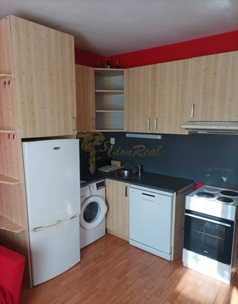 Kuchyňský kout s dřevěným dekorem a spotřebiči v 1-pokojovém bytě.