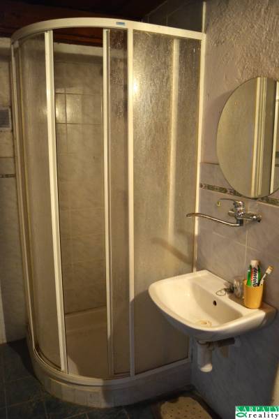 Koupelna v rodinném domě s rohovým sprchovým koutem a umyvadlem.