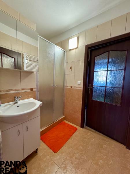 Koupelna se sprchovým koutem a umyvadlem v 3-pokojovém bytě, dlaždice a zrcadlo.