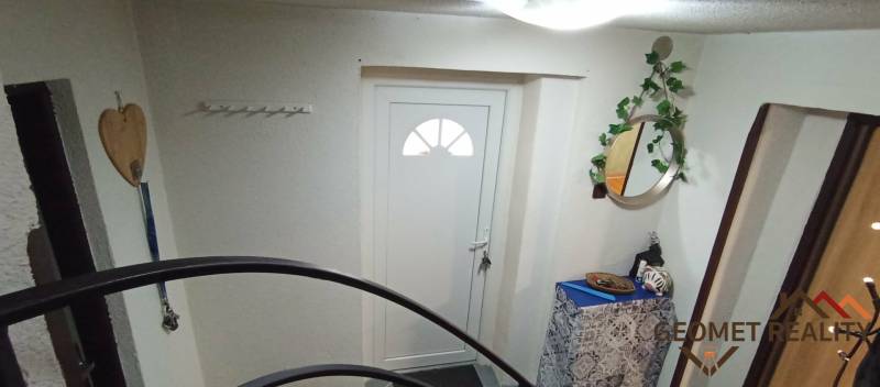 Vstup do rodinného domu s bílými dveřmi, zrcadlem a dekorativními prvky.