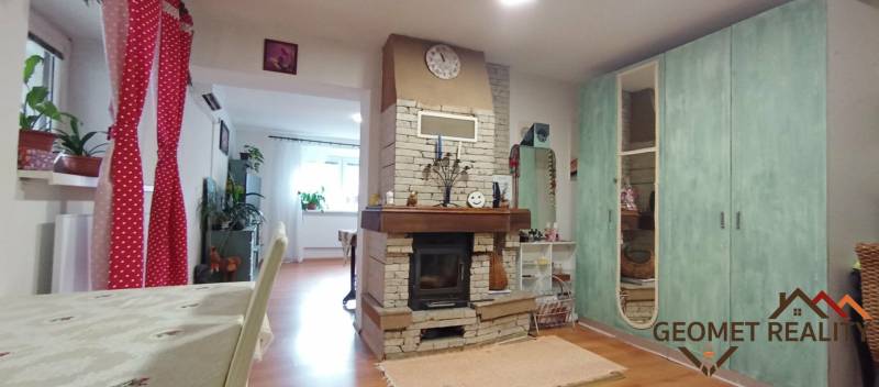 Interiér rodinného domu s krbem a podlahou s dřevěným dekorem, doplněný pestrou výzdobou.