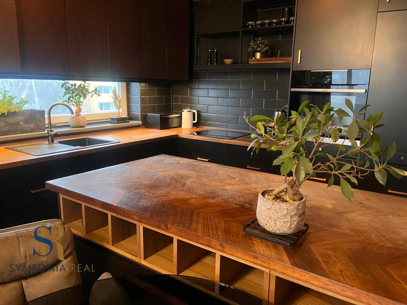 Kuchyně v 2pokojovém bytě s podlahou s dřevěným dekorem a černou kuchyňskou linkou.