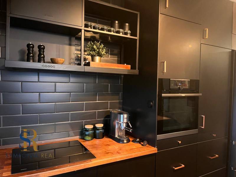 Kuchyně s černými skříňkami v 2-pokojovém bytě a podlahou s dřevěným dekorem.