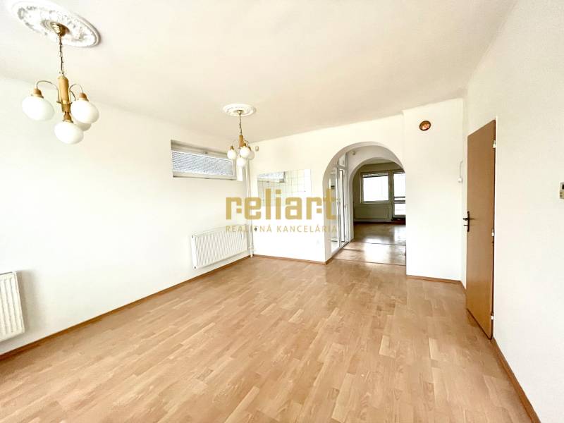 Interiér rodinného domu s podlahou s dřevěným dekorem a zdobeným osvětlením.