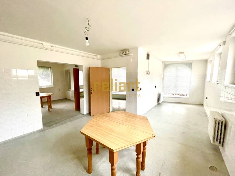 Prostorný pokoj s dřevěnými stoly a radiátory v rodinném domě.