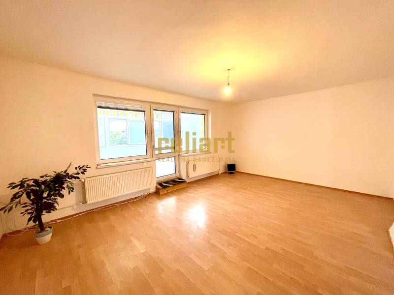 Pokoj v rodinném domě s podlahou s dřevěným dekorem a velkými okny.