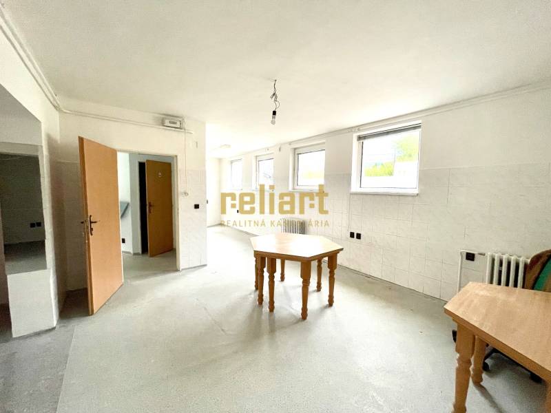 Interiér rodinného domu s prázdnou místností, stoly a bílými stěnami.