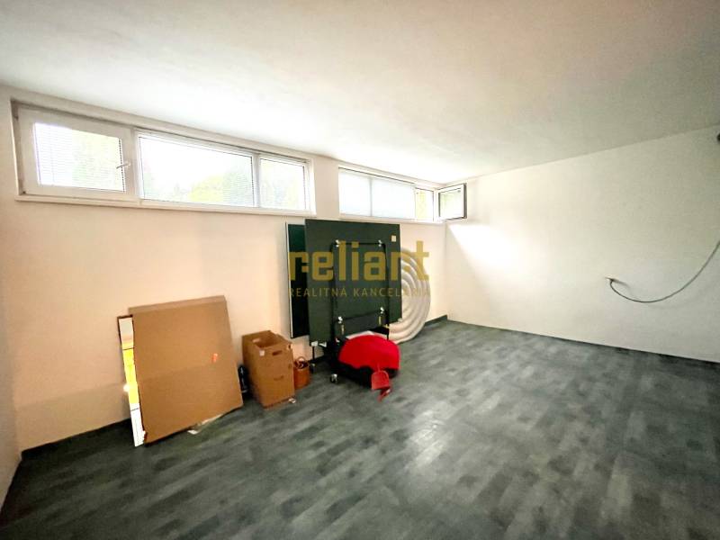 Pokoj v rodinném domě s podlahou s dřevěným dekorem, okny a kartonovými krabicemi.